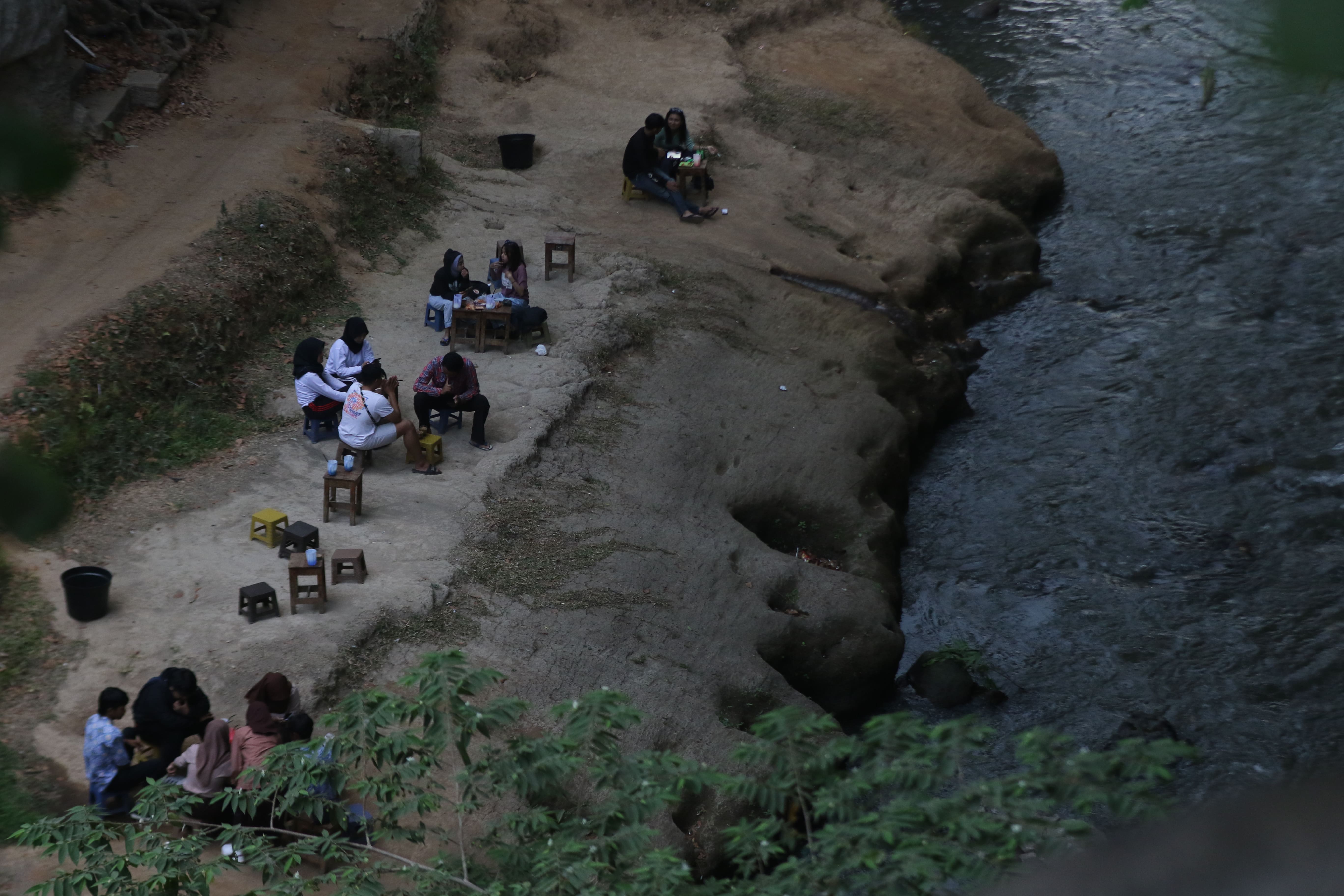 MENYATU DENGAN ALAM: Para pelajar dan mahasiswa ngopi sambil menikmati suasana gemericik air di Sungai Brantas, Jumat lalu (13/10). Keberadaan warkop berada di sekitar kolong jembatan Van Riebeek