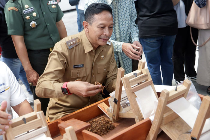 Pj Wali Kota Malang Wahyu Hidayat mencoba proses melinting tembakau industri.