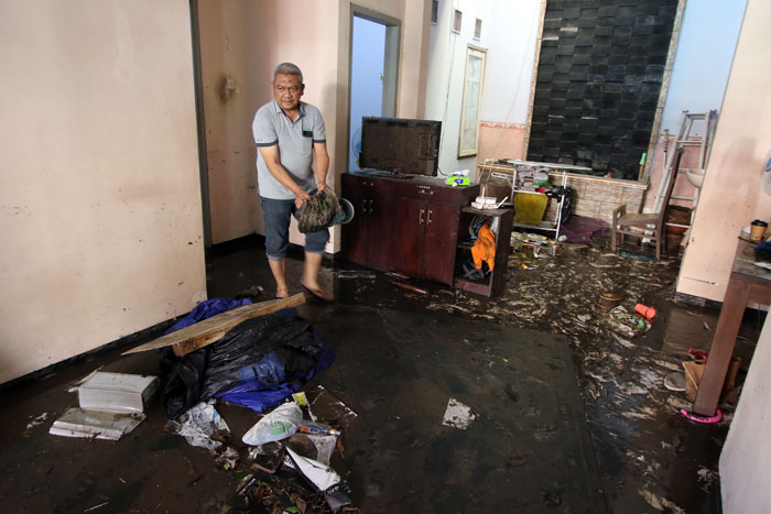 BERSIH-BERSIH: Warga Perumahan Sigura-gura Residence membersihkan rumahnya yang kemasukan banjir