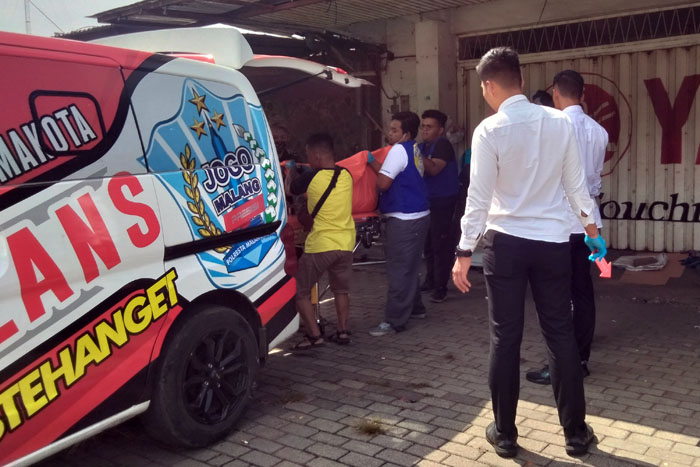 DALAM PENYELIDIKAN: Relawan dan warga mengevakuasi jenazah pria yang ditemukan di depan dealer motor Jalan Satsui Tubun nomor 44, Kebonsari, Sukun, Kota Malang kemarin