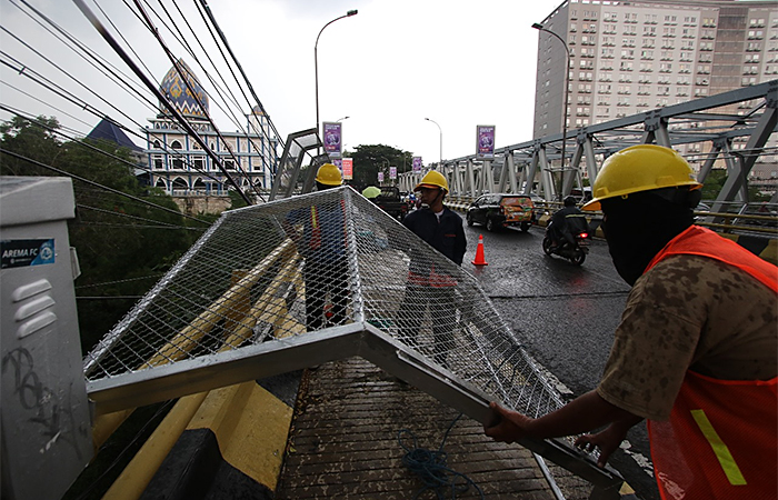 Pekerja memasang pagar pengaman berbentuk jaring berbahan besi di Jembatan Jalan Soekarno-Hatta kemarin (5/12).