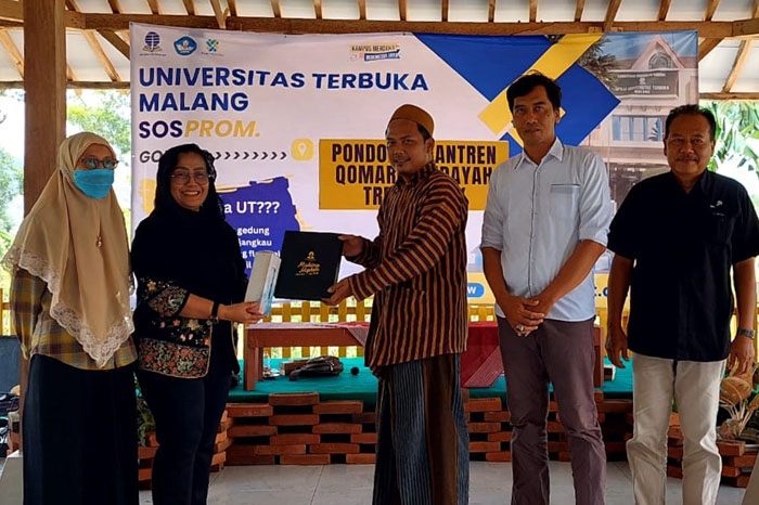Direktur UT Malang Dr. Lilik Sulistyowati menyerahkan merchandise kepada pengasuh ponpes Qomarul Hidayah