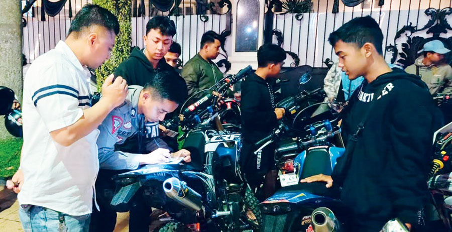 Personel Polresta Malang Kota menilang pengendara motor yang menggunakan knalpot brong di Jalan Ijen, Minggu dini hari (10/12).