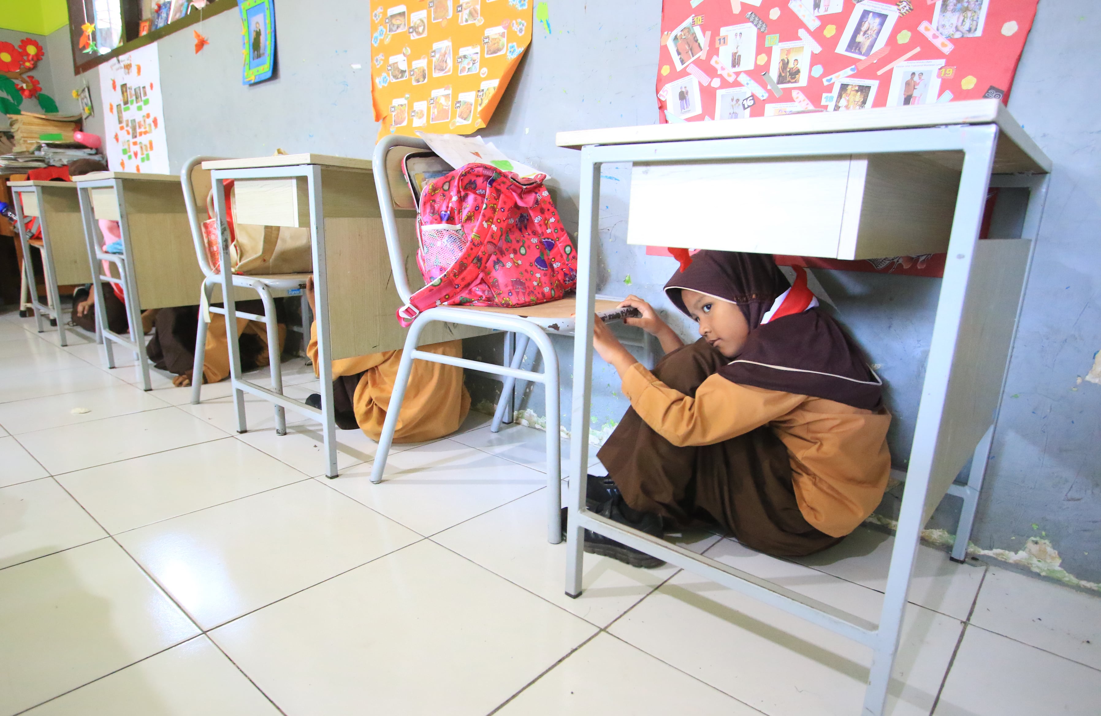 SIAGA BENCANA: Para siswa SDN Tanjungrejo 5 mengikuti simulasi tanggap bencana kemarin (20/12). Mereka diajar cara melindungi diri dan evakuasi jika terjadi gempa.