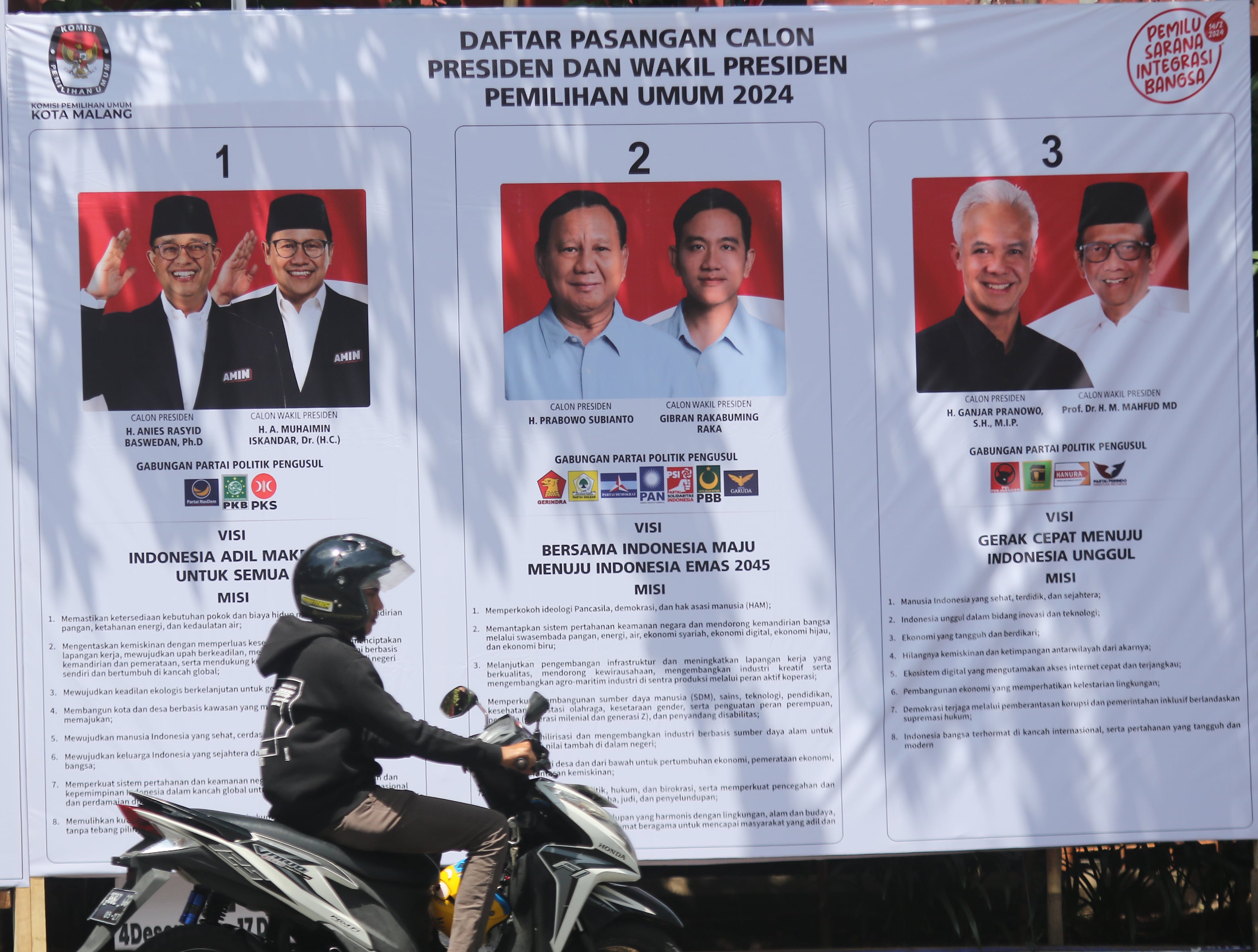 MASA KAMPANYE: Seorang pengendara melintasi baliho milik KPU Kota Malang yang memajang tiga pasangan capres-cawapres kemarin.