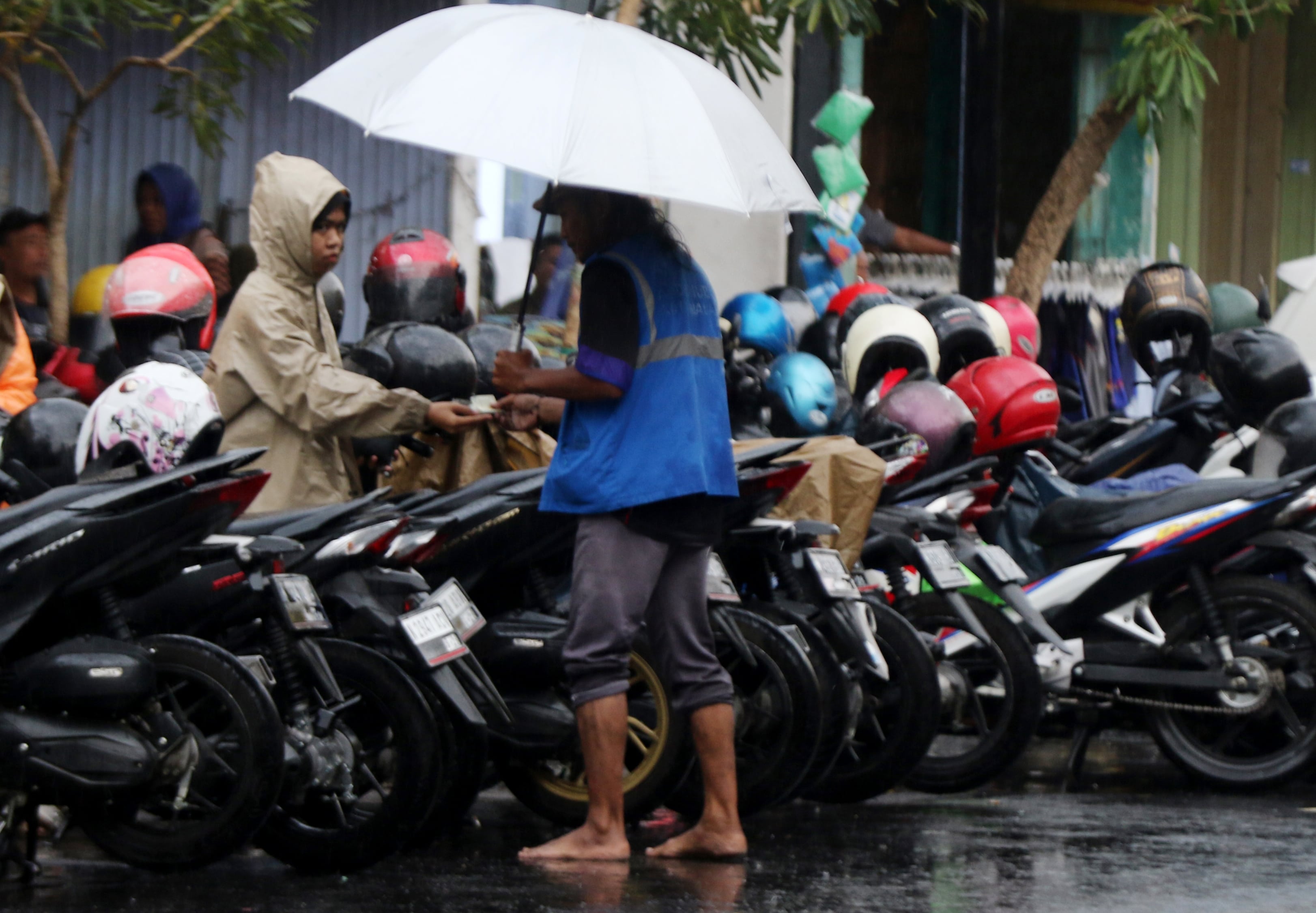 HARUS PROFESIONAL: Salah seorang juru parkir (jukir) menerima uang parkir dari pengendara.