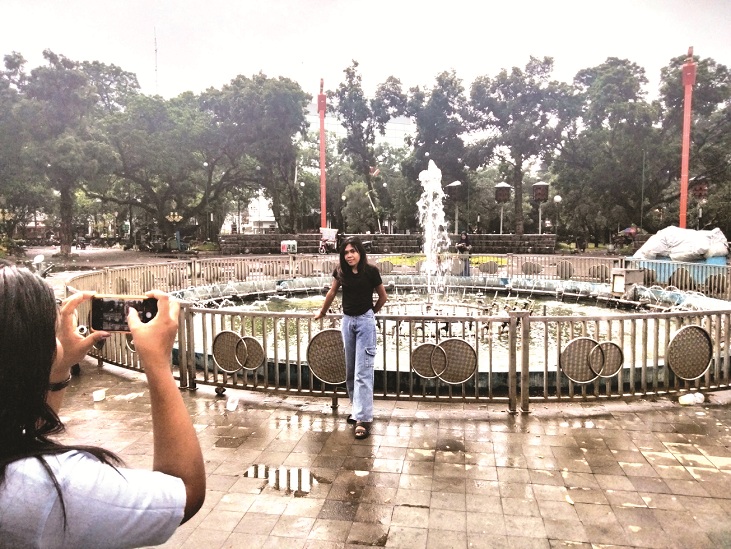 SEGERA DIREVITALISASI: Pengunjung Alun-Alun Merdeka mengabadikan momen di sekitar air mancur. (Nabila Amelia/Radar Malang)