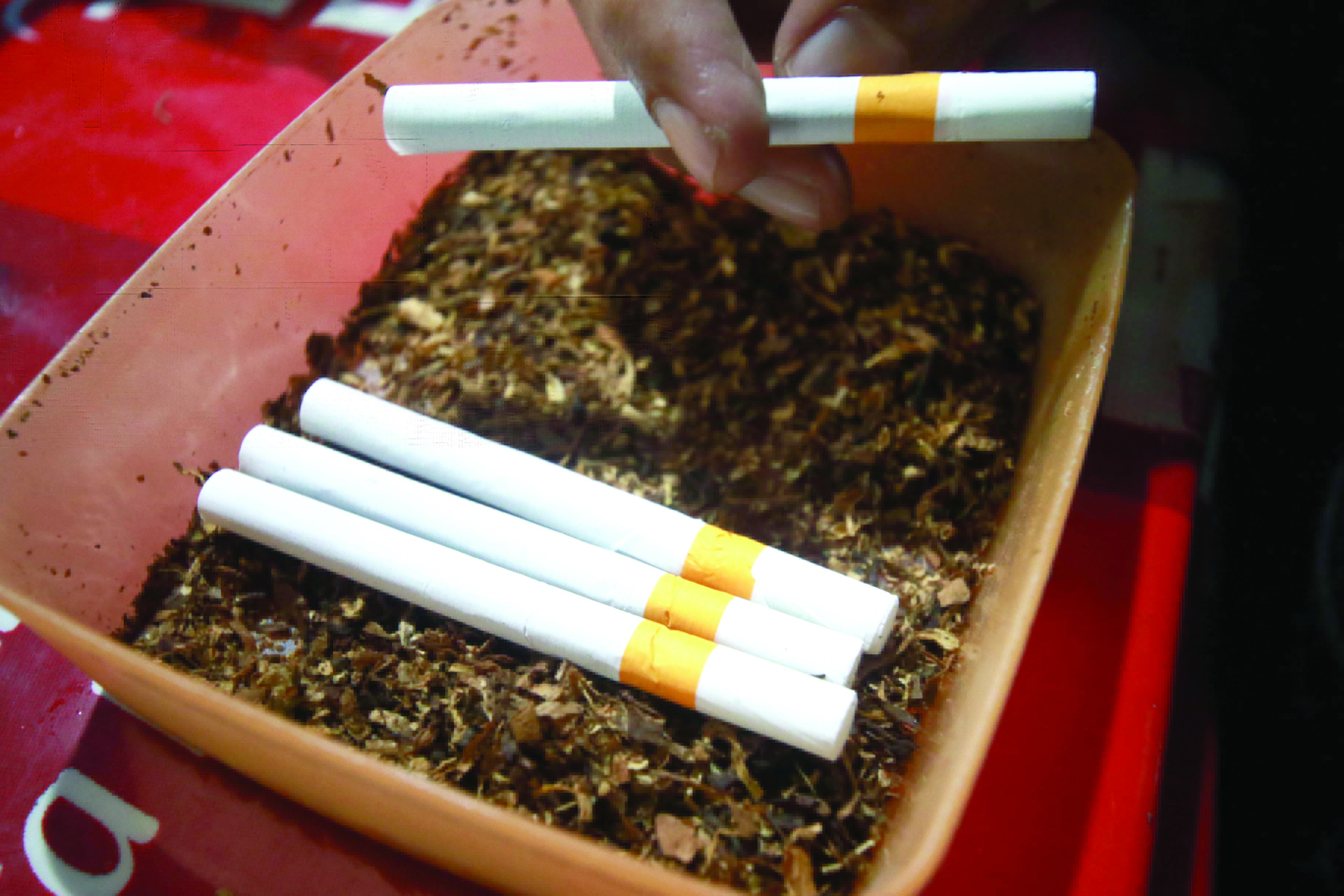 IMBAS CUKAI NAIK: Seseorang melinting rokok di rumahnya kemarin. Hal itu dilakukan untuk menyiasati mahalnya harga rokok.