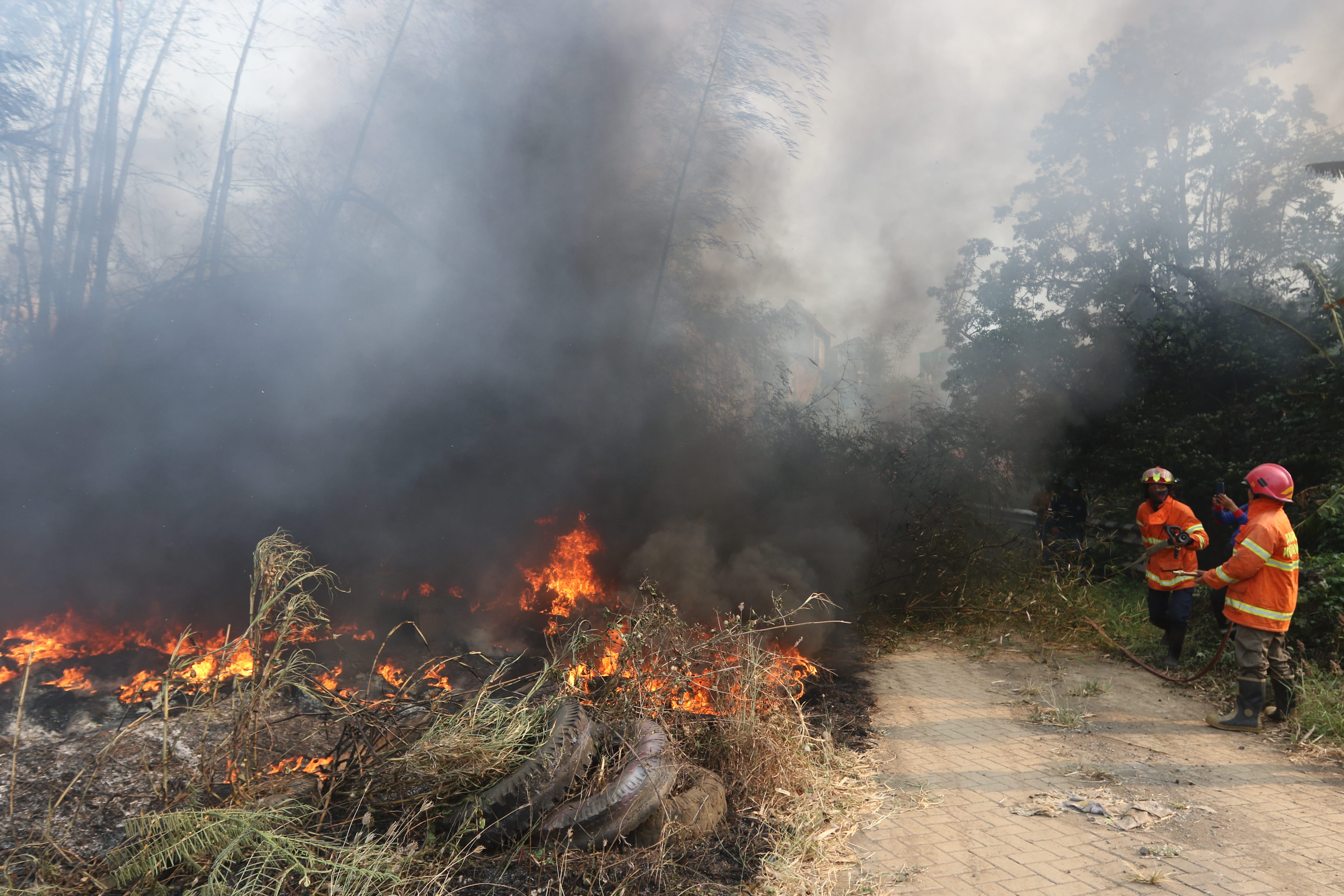 SELALU SIAGA: Personel Damkar Kota Malang memadamkan kobaran api yang menghanguskan lahan di kawasan Tunjungsekar.