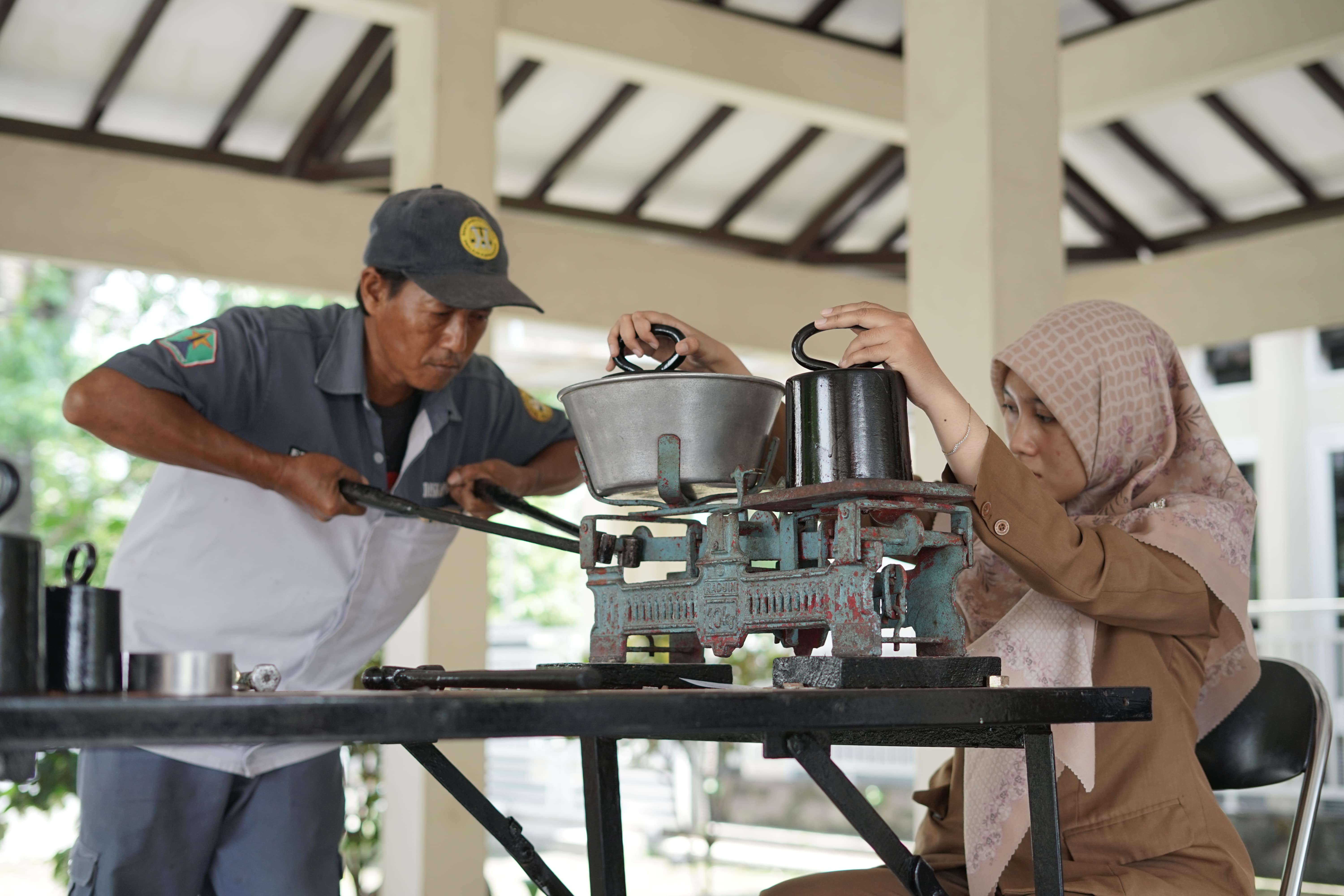 ALAT UKUR: Penera terampil dari Diskopindag Kota Malang Lutfia Silvi melakukan pengecekan akurasi timbangan di kantor Kelurahan Cemorokandang kemarin.