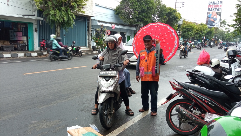 SIAPA PAKAI QRIS?: Salah seorang jukir di Jalan Ahmad Yani, Kepanjen melayani warga yang parkir di kawasan tersebut.  &nbsp;