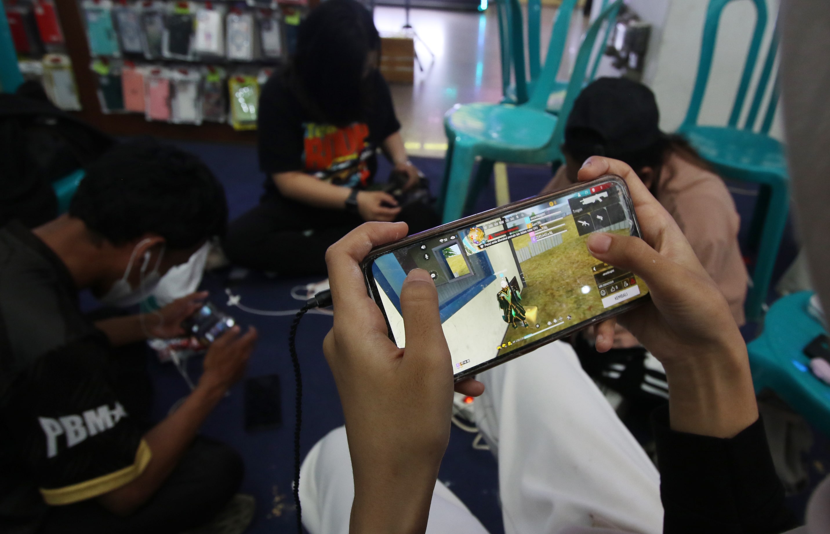 KOMPAK: Lima remaja duduk membentuk lingkaran di lantai dasar Cyber Mall Malang Minggu lalu (14/1). Mereka bermain game free fire.