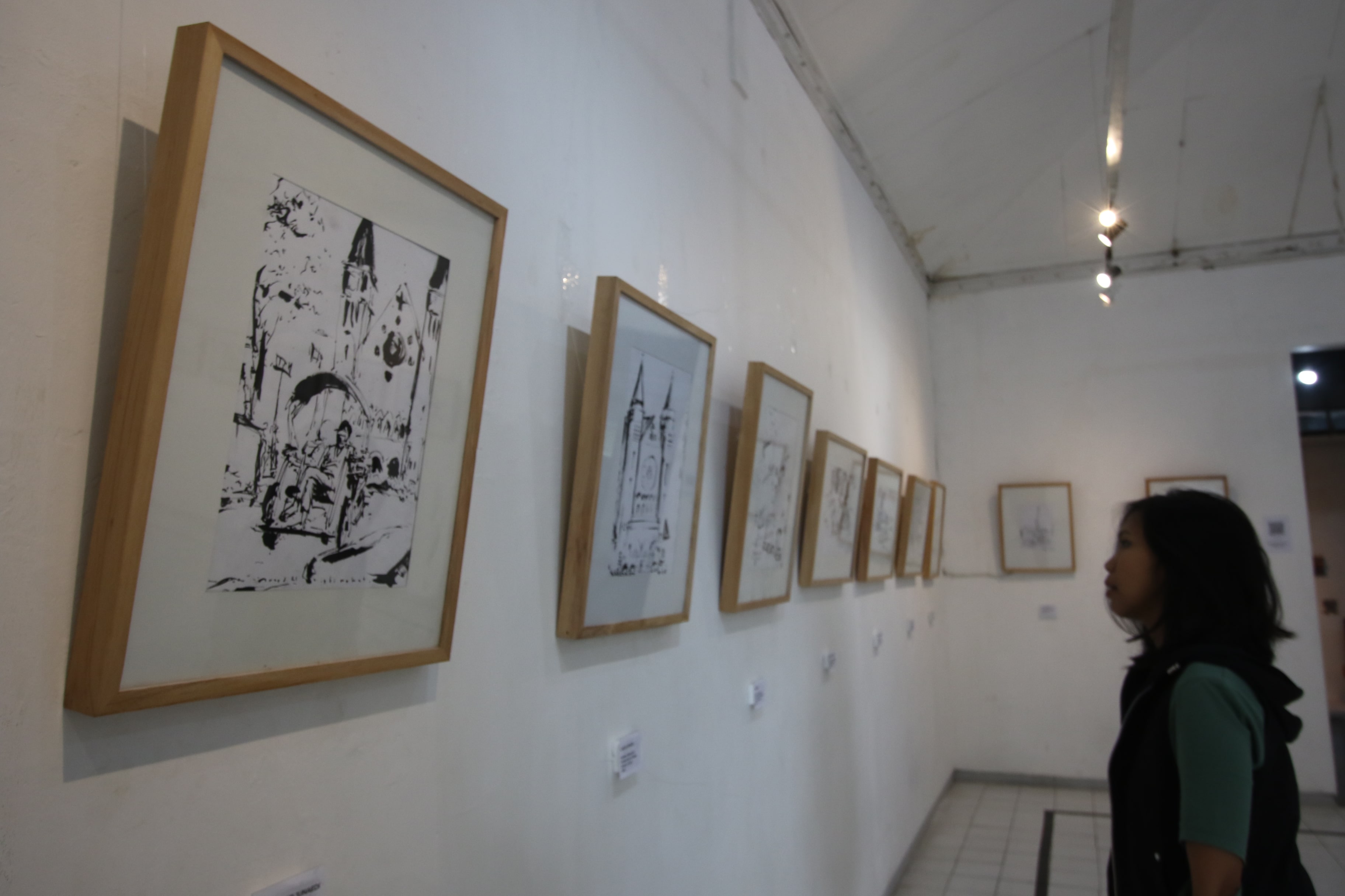PAMERAN SKETSA: Salah seorang pengunjung memperhatikan deretan sketsa di gedung Dewan Kesenian Malang (DKM) kemarin.