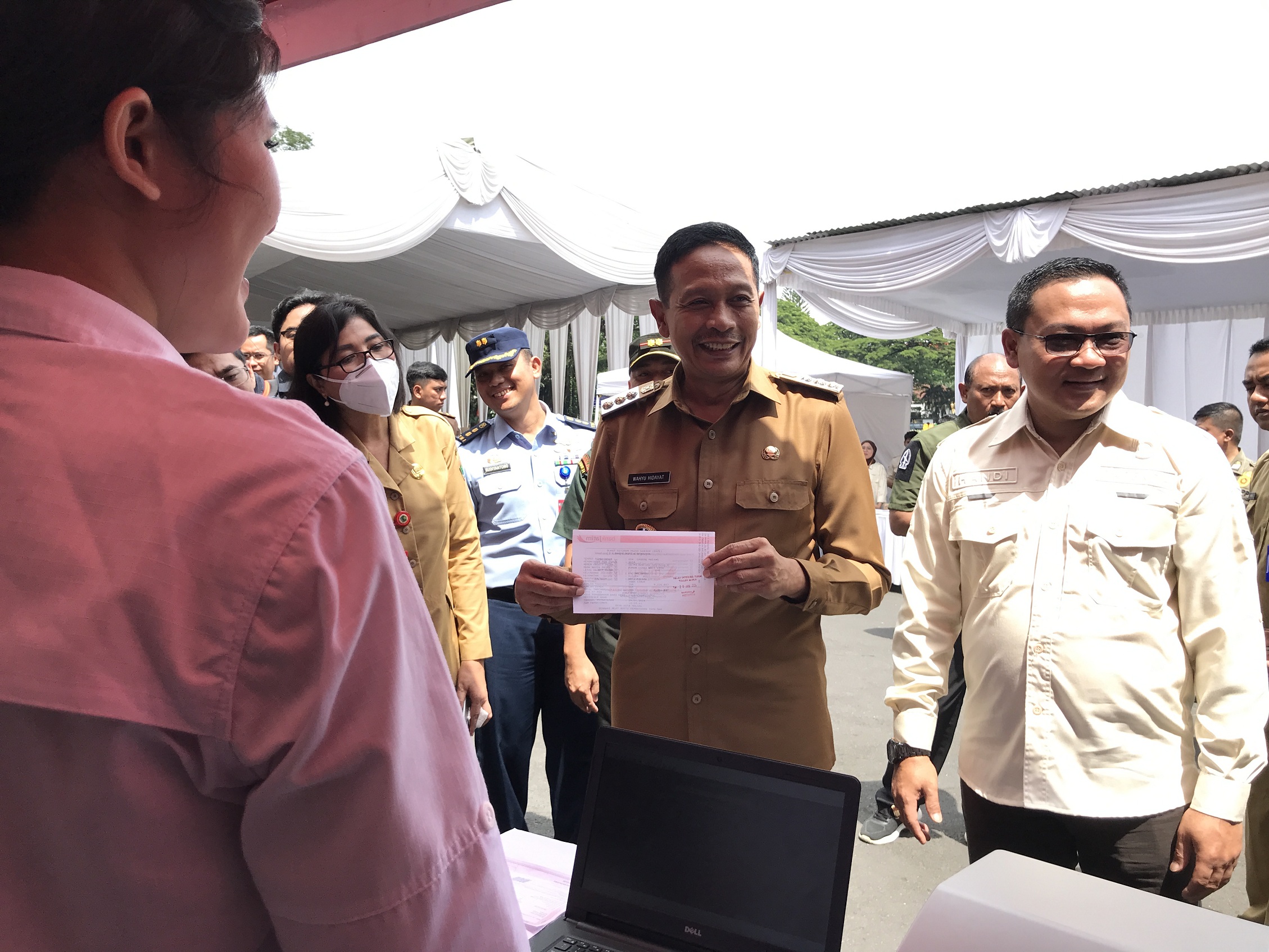 BISA LANGSUNG BAYAR: Pj Wali Kota Malang Wahyu Hidayat menunjukkan SPPT PBB 2024 di loket pembayaran ditemani Kepala Bapenda Handi Priyanto. (Satria Cahyono/Radar Malang)