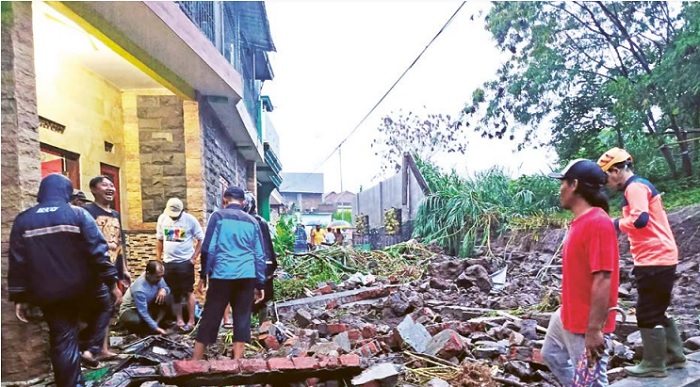 AMBROL Petugas BPBD dan warga berusaha membersihkan material plengsengan dan tembok yang menutup Jalan Damin di Desa Beji, Kecamatan Junrejo, Kota Batu, Senin sore (291).