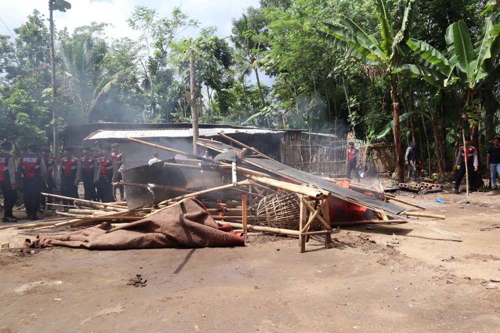 DIMUSNAHKAN: Sejumlah petugas membongkar dan membakar tempat yang diduga untuk judi sabung ayam di Dusun Ngempit, Desa Tegalsari, Kecamatan Kepanjen.