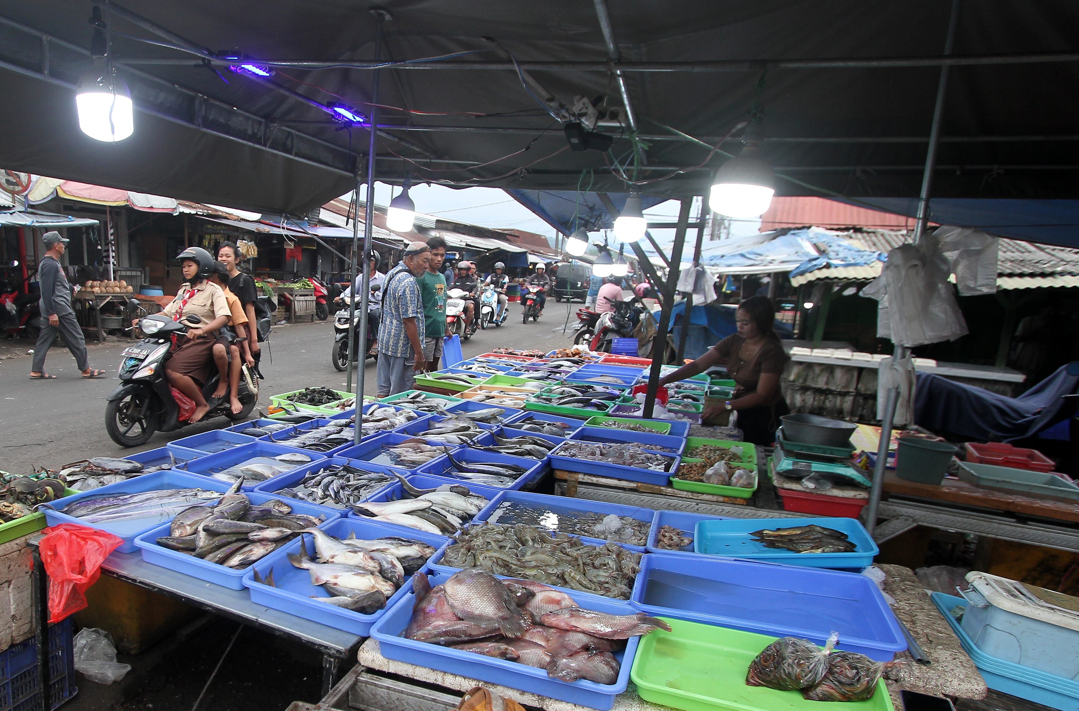 TRANSAKSI ELEKTRONIK: Seorang pedagang di Pasar Induk Gadang (PIG) menyuguhkan dagangannya kemarin. Mereka rutin membayar retribusi ke diskopindag.