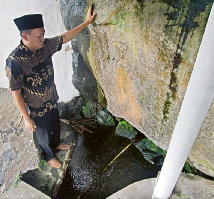 DI BAWAH BATU: Edi Sutrisno menunjukkan titik mata air Sumber Manggis yang berada di Dusun Segelan, Desa Balesari, Kecamatan Ngajum, Kabupaten Malang.