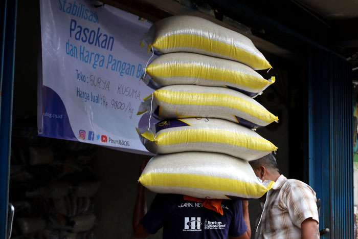 Seorang kuli panggul memikul tumpukan beras di Pasar Besar Malang. Harga beras premium mulai menurun karena intervensi Bulog