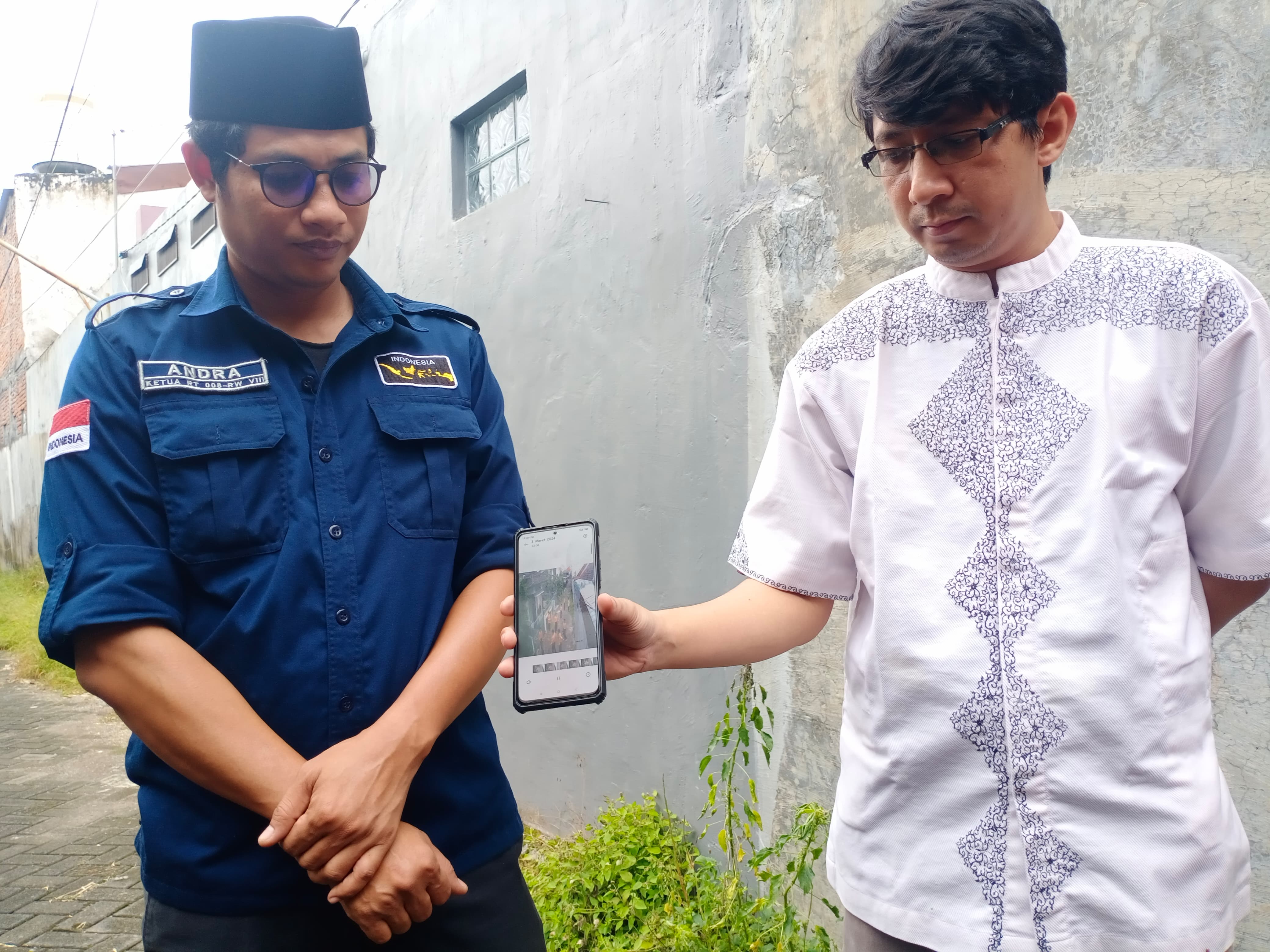 Ketua RT 08/RW 08, Chandra K Seputro (kiri) bersama warganya menunjukkan barang bukti rekaman CCTV yang memperlihatkan adegan perundungan atau bullying siswa SMP di Sukun Kota Malang