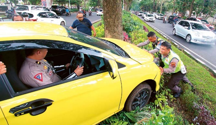 LAKA TUNGGAL: Mobil Daihatsu Ayla dengan nopol N 1291 ACI ringsek bagian depan setelah menerobos taman median jalan di Jalan Veteran kemarin
