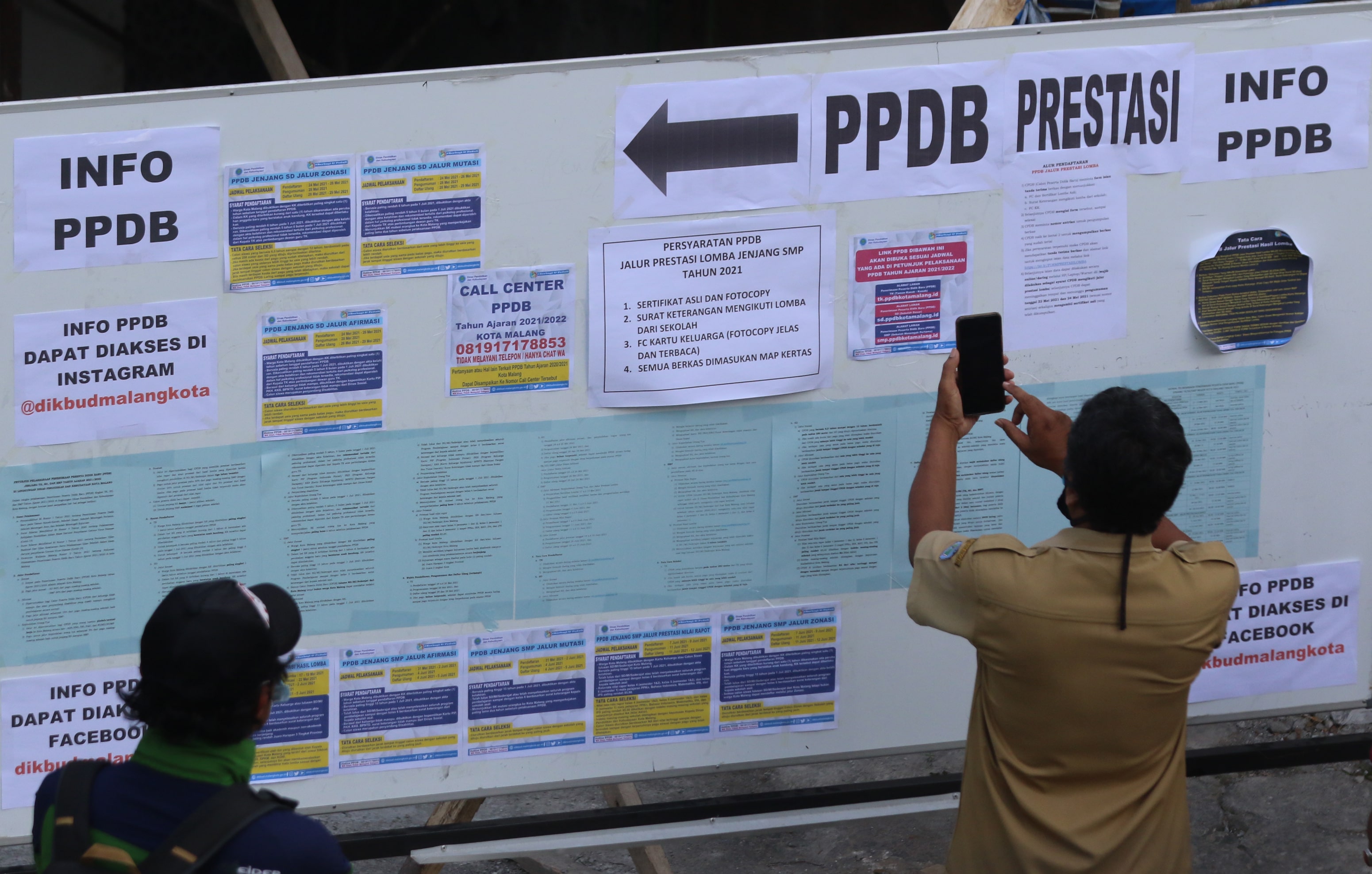 SAMBUT PPDB: Seorang guru memotret alur PPDB di papan pengumuman area kantor Disdikbud Kota Malang.