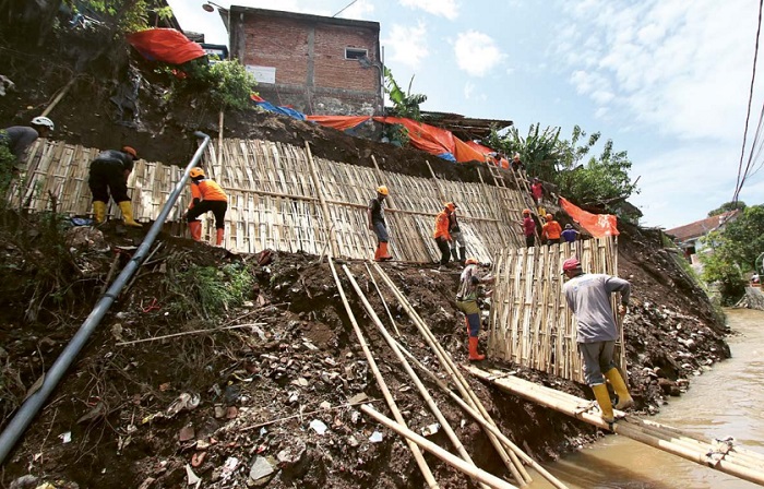 ANTISIPASI: Para pekerja memasang dinding bambu dan terpal untuk memperkuat tebing di Jalan Sukun Gempol Kelurahan Tanjungrejo, Sukun, kemarin (15/3).
