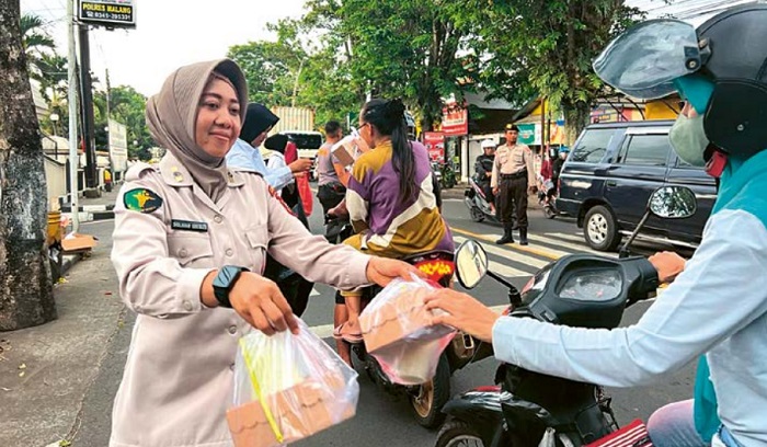 BERBAGI: Petugas membagikan takjil kepada pengendara yang melintas di depan Mapolres Malang sore kemarin (15/3).