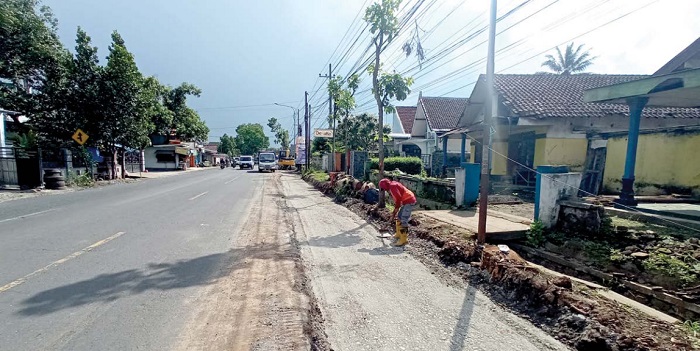 MAKIN LEBAR: Seorang pekerja membersihkan bagian pinggir jalan yang telah dicor di jalur Kepanjen-Karangkates yang dilakukan pelebaran jalan.