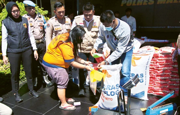 ILEGAL: Enik Heriyanti mempraktikkan cara mengemas ulang beras Bulog kemasan 50 kilogram menjadi beras premium kemasan lima dan 25 kilogram.