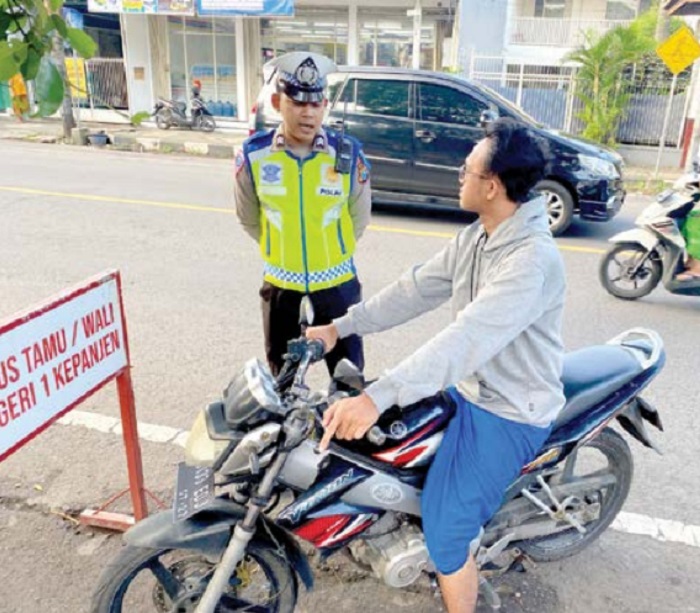 TEGURAN SIMPATIK: Petugas menghentikan pengendara sepeda motor yang tak memakai helm di Jalan Kawi, Kepanjen.