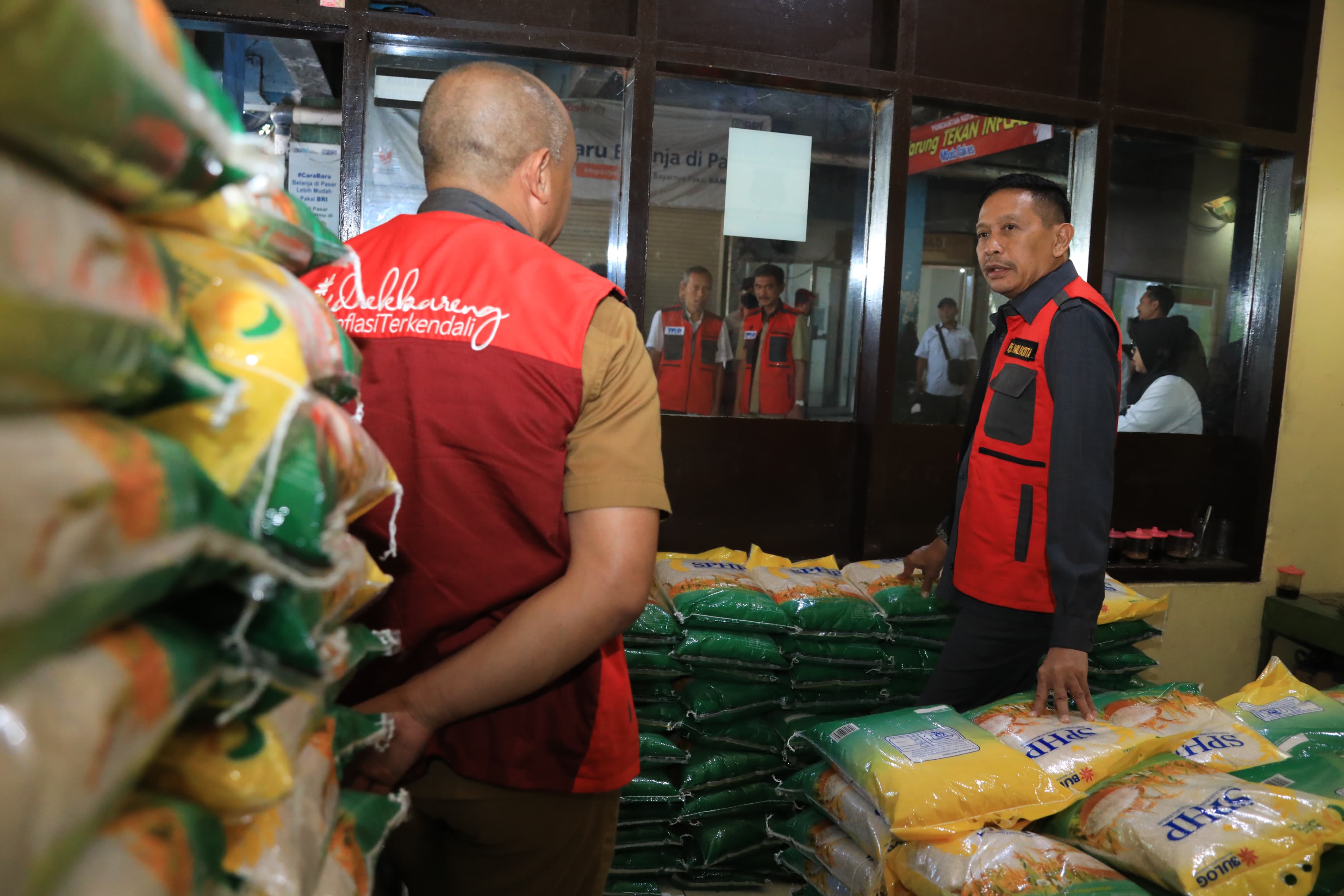 Pj Wali Kota Malang Wahyu Hidayat (kanan) berbincang dengan Eko Sya Kepala Disperindag di antara tumpukan beras Bulog dalam ruangan Warung Tekan Inflasi Pasar Besar