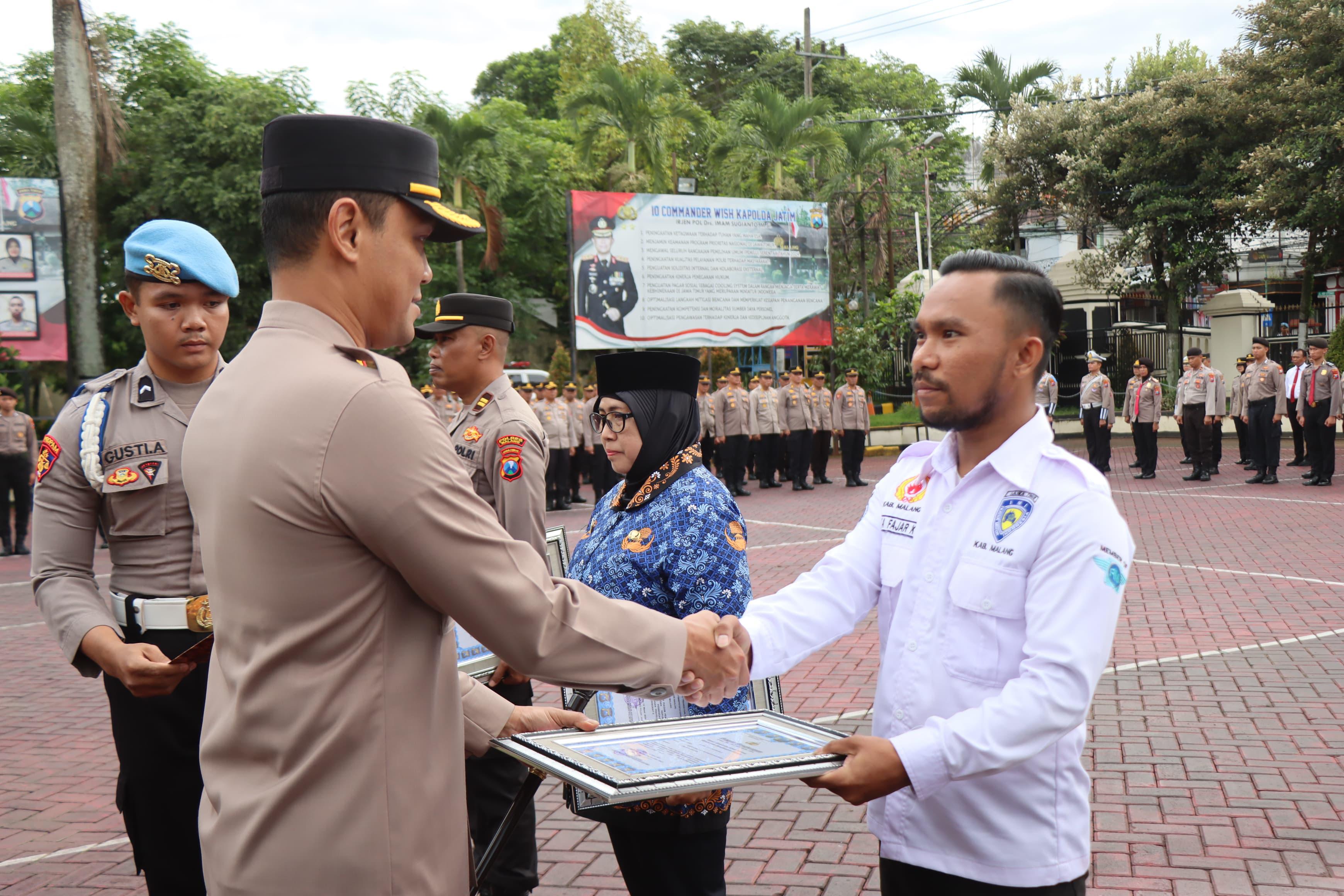 Kapolres Malang AKBP Putu Kholis Aryana menyerahkan penghargaan pada pengurus IMI Kabupaten Malang Andika Fajar Kurniawan atas kesuksesan Kanjuruhan Street Race menekan balapan liar di Kepanjen