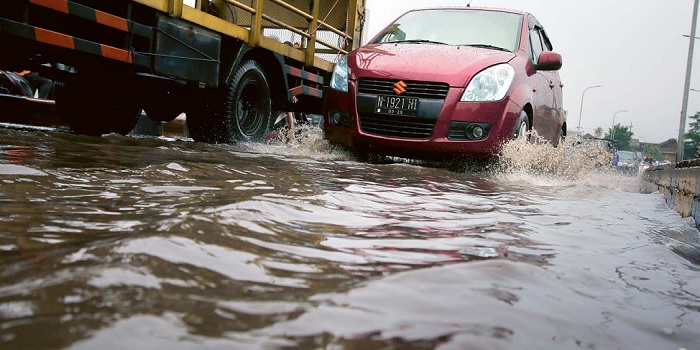 AKIBAT HUJAN DERAS: Beberapa mobil melintasi jembatan Kedungkandang yang terendam air kemarin (22/3). Genangan mengakibatkan kepadatan arus lalu lintas.