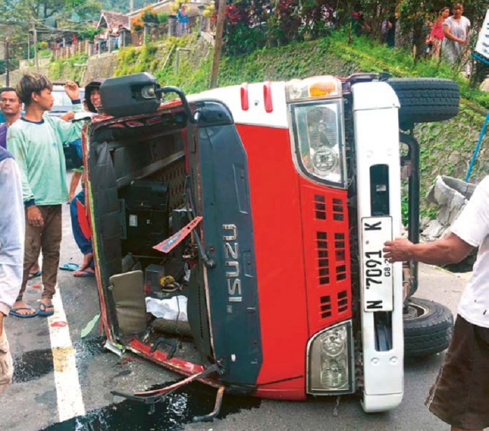 RUSAK: Isuzu ELF terguling di Jalan Raya Ngantang setelah gagal mendahului mobil pikap  dan menghantam pot semen di tepi jalan kemarin siang (24/3).