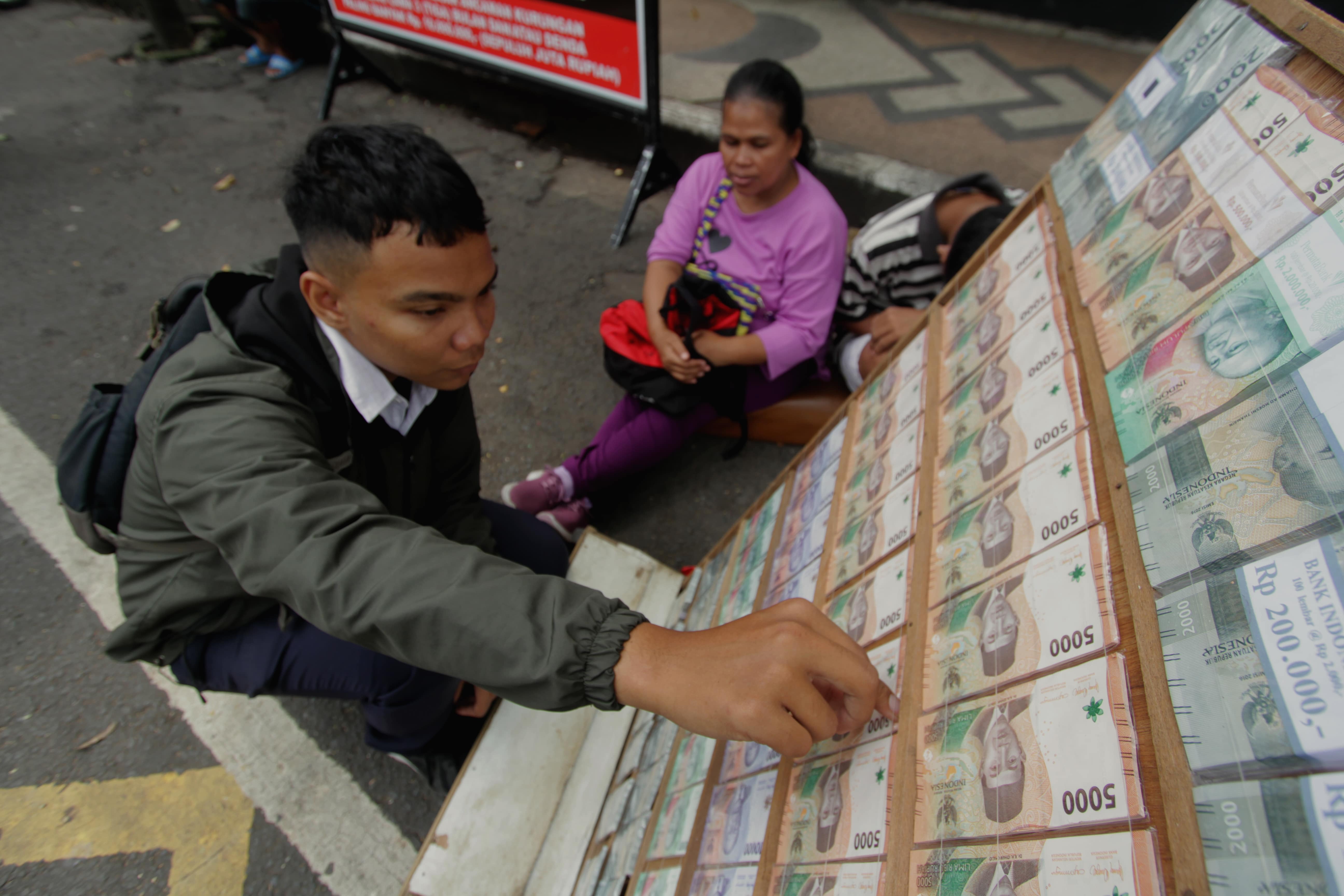 MULAI MARAK: Salah satu penyedia jasa penukaran uang baru jalanan mangkal di Jalan Merdeka Timur kemarin (25/3). Dalam sehari bisa menghabiskan Rp 5 juta sampai Rp 10 juta.