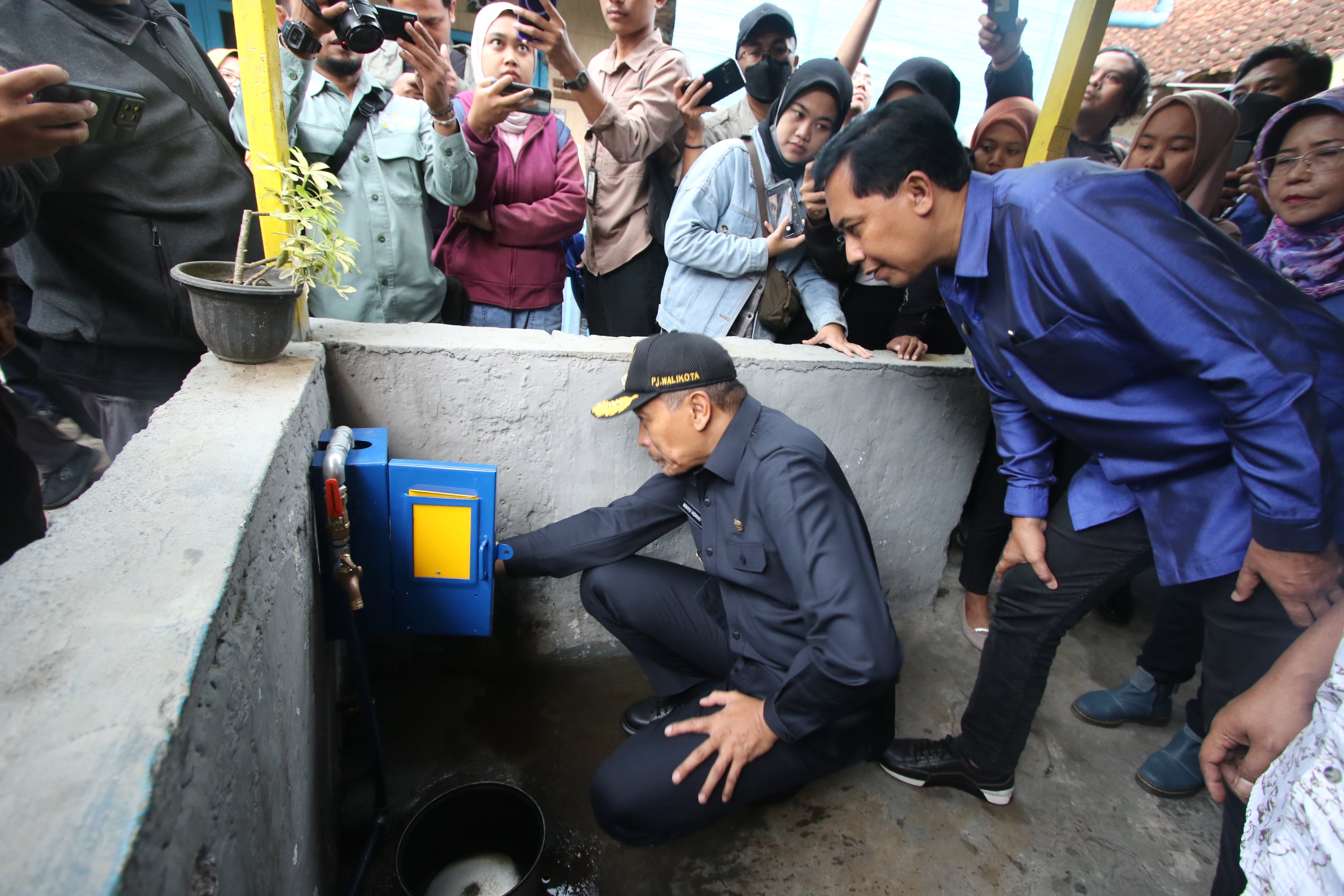 PROGRAM KEJUTAN: Pj Wali Kota Malang Wahyu Hidayat (duduk) mengecek instalasi salah satu rumah warga yang mendapatkan pemasangan saluran PDAM gratis kemarin.