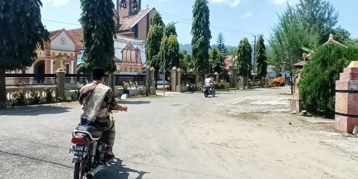 KAMPUNG TOLERANSI: Seorang umat Islam di Desa Pujiharjo, Kecamatan Tirtoyudo, terlihat akan beribadah dengan melintas di depan gereja terbesar di desa tersebut.