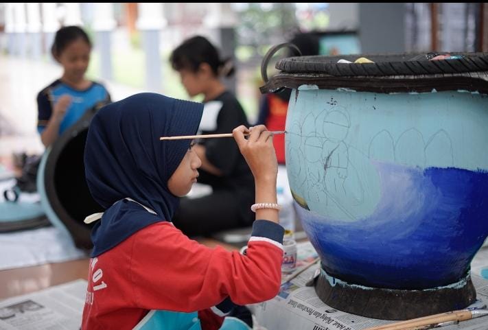 DUKUNG KREATIVITAS: Salah satu anak tengah melukis bak sampah di Kota Batu Selasa (2/4).