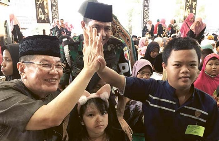 HIGH FIVE: Komisiaris Utama PT ACA Iwan Kurniawan melakukan tos atau high five dengan Rayhan, salah satu bocah penerima santunan saat di Pendopo Kawedanan Singosari, Jumat (5/4) kemarin.