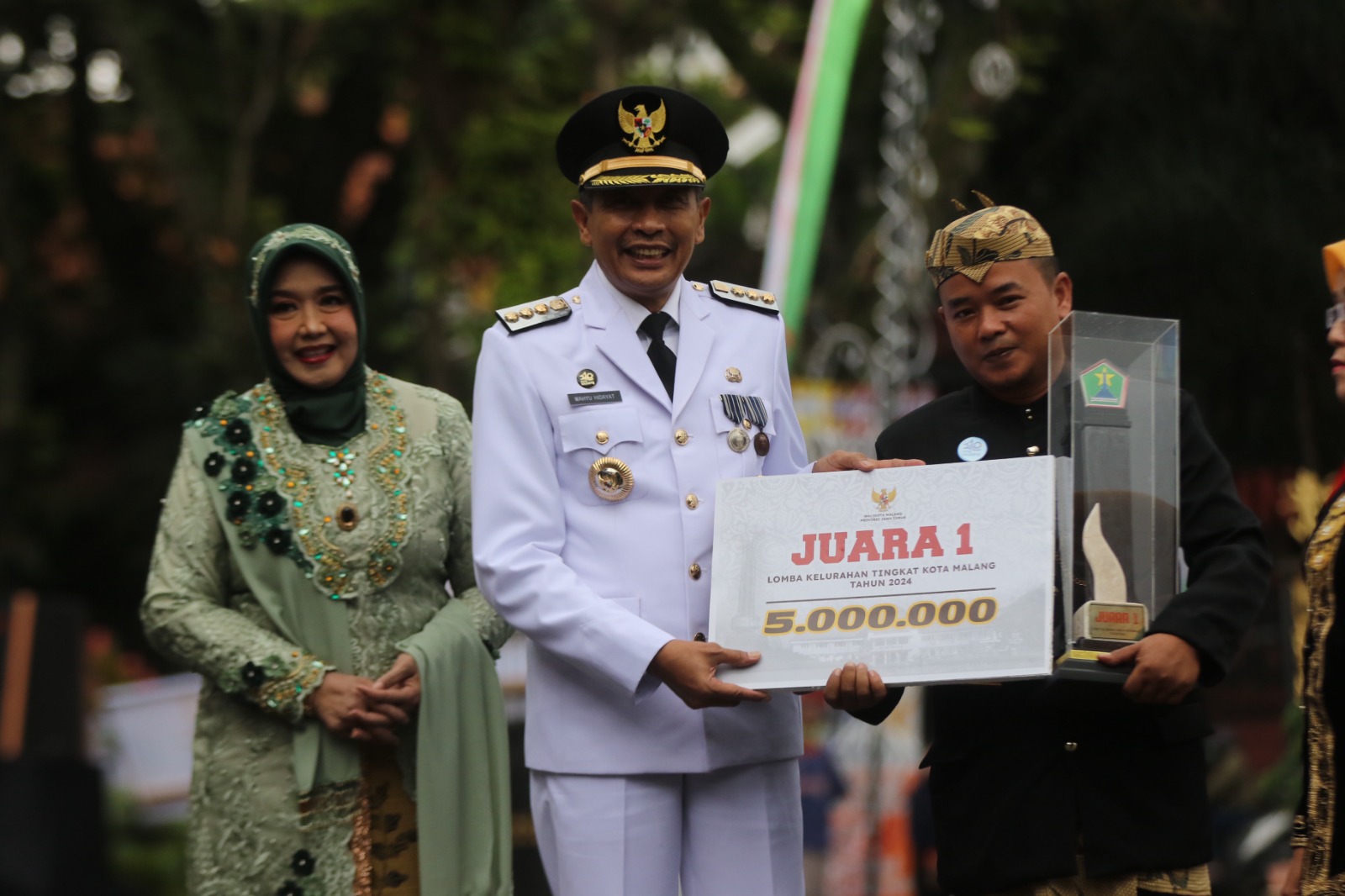 JAWARA: (dari kiri) Pj Ketua TP PKK Kota Malang Hanik Andriani Wahyu Hidayat, Pj Wali Kota Malang Wahyu Hidayat, dan Lurah Gadang Denny Surya Wardhana membawa plakat dan piala Juara 1 Lomdeskel 2024