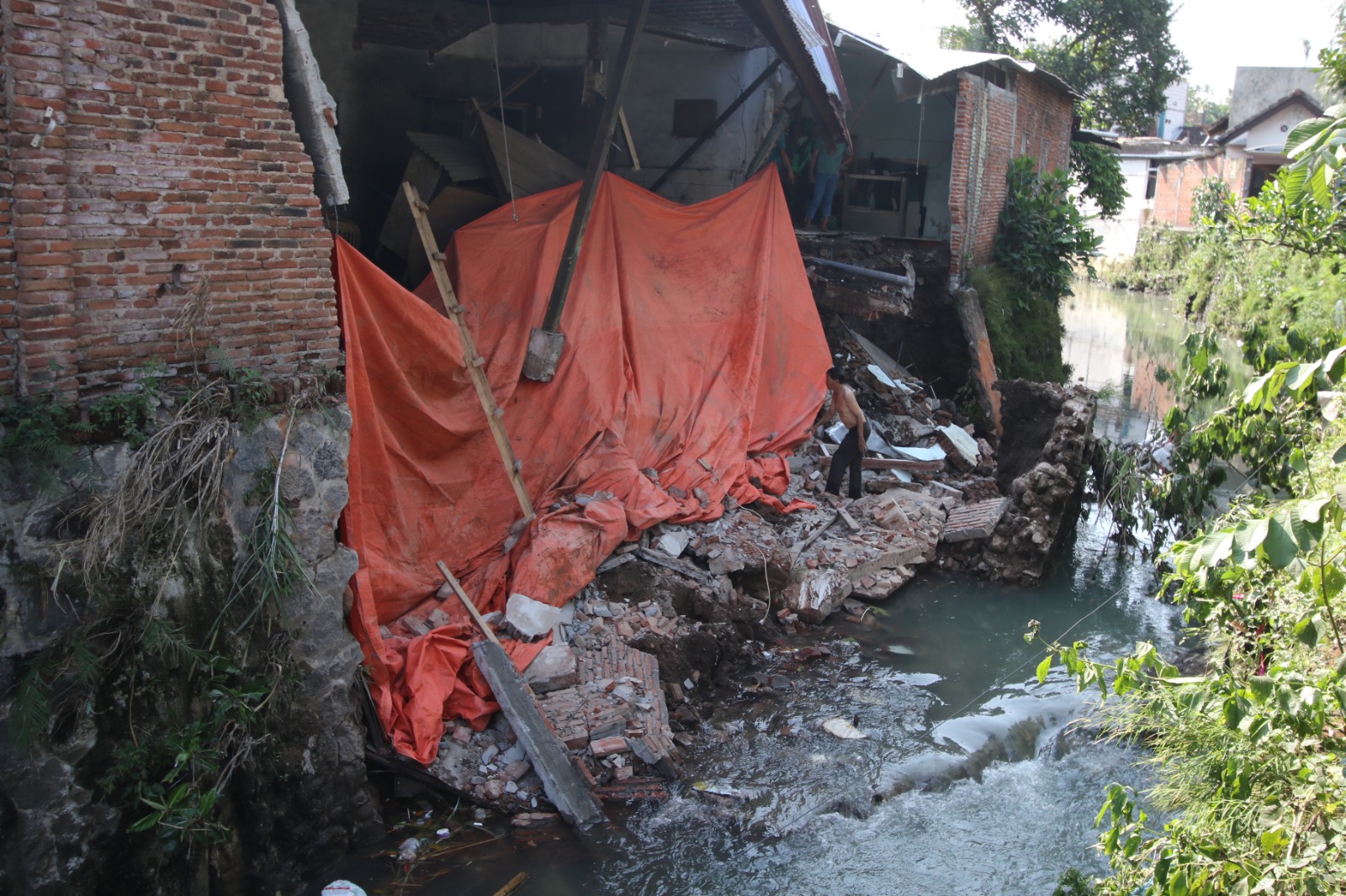 DITUTUP TERPAL: Bagian belakang dua rumah di Jalan Hamid Rusdi Gang 3, nomor 234, RT 2/RW 12, Kelurahan Bunulrejo, Kecamatan Blimbing ambrol terbawa longsor.