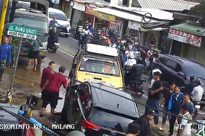 Tangkapan layar CCTV Kota Malang yang menunjukkan mobil Toyota terperosok di lubang saluran PDAM yang ambrol.