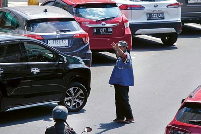 SEGERA PAKAI QRIS: Salah satu jukir di koridor Kajoetangan memberi aba-aba untuk salah satu pengendara mobil, kemarin.