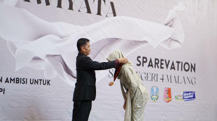 MOMEN HARU : Penyematan tanda Purnawiyata oleh Kepala SMAN 4 Malang  Dr Hari Wahjono SPd MPd (kiri) kepada siswi kelas XII.