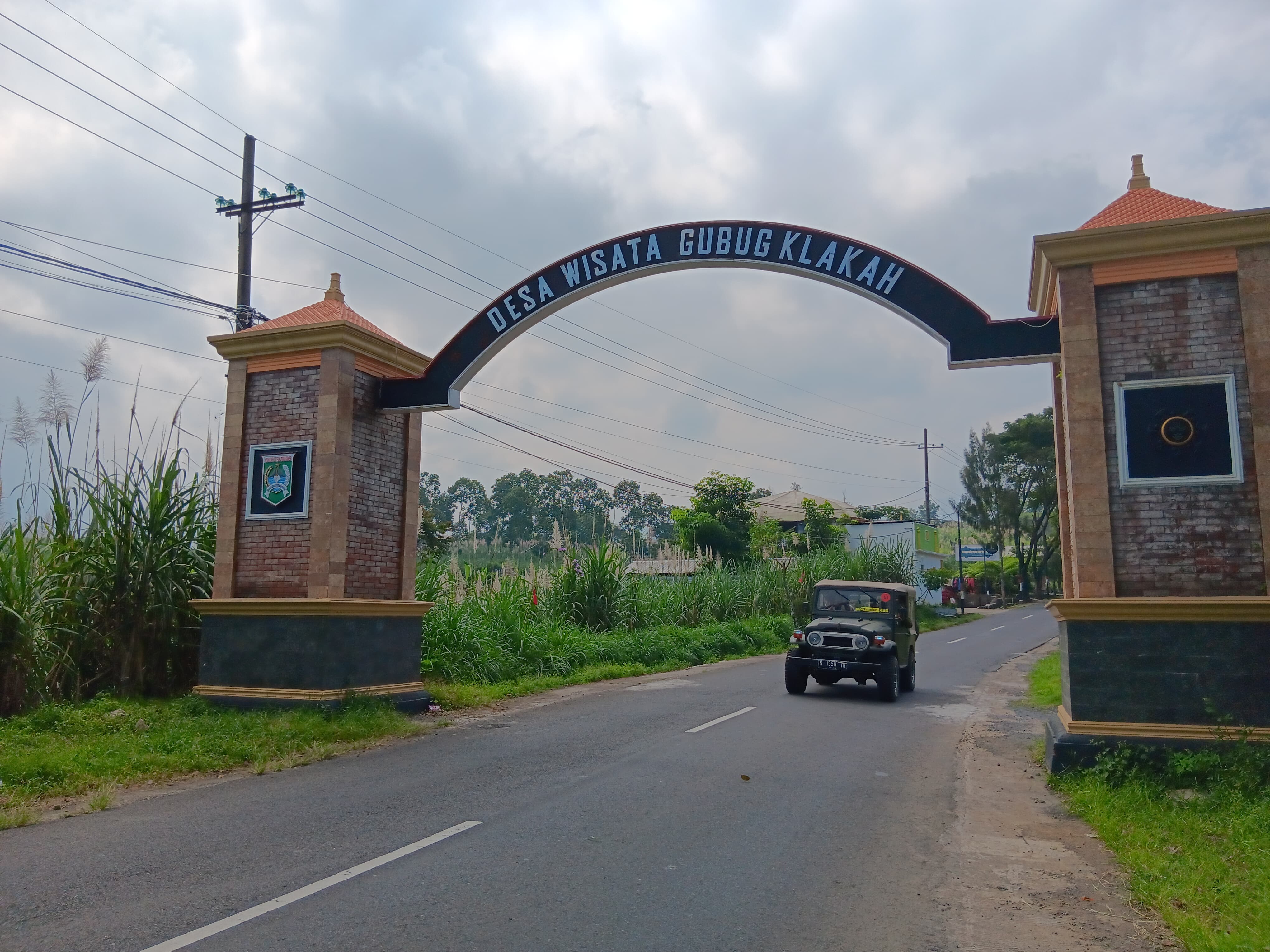 DESTINASI: Mobil wisatawan melintasi gerbang Desa Wisata Gubugklalah, Kecamatan Poncokusumo, Kabupaten Malang kemarin.
