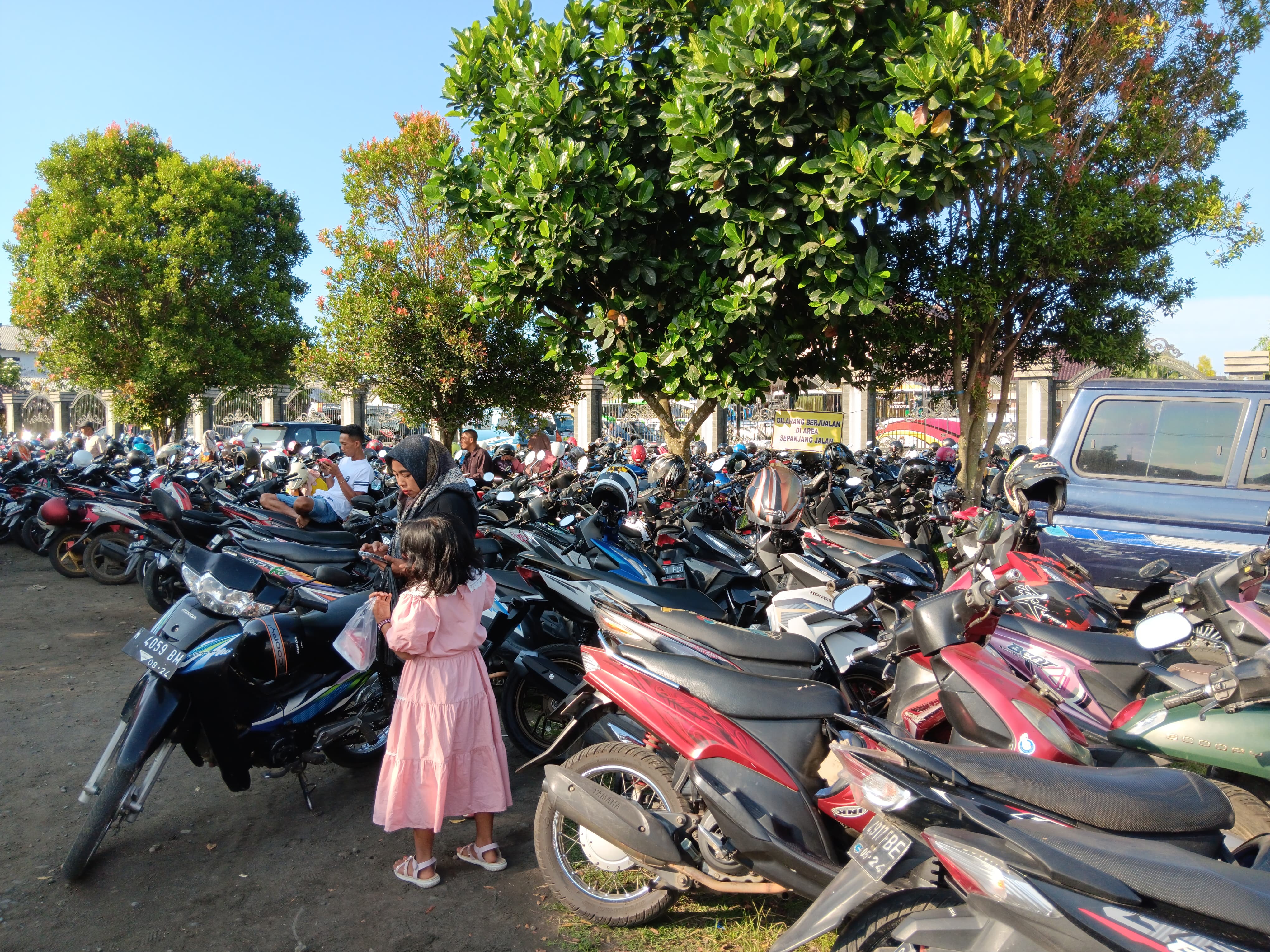 RETRIBUSI: Seorang juru parkir (jukir) menjaga kendaraan di acara HUT Ikatan Guru TK Seluruh Indonesia (IGTKI) di Talok, Turen.