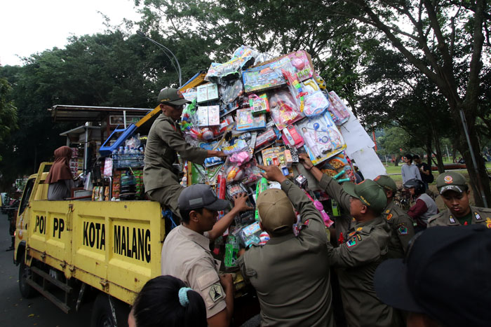 SERING KUCING-KUCINGAN: Petugas gabungan mengangkut dagangan PKL liar di kawasan Alun-Alun Merdeka Malang, kemarin. Mereka kedapatan berjualan hingga ke dalam alun-alun.