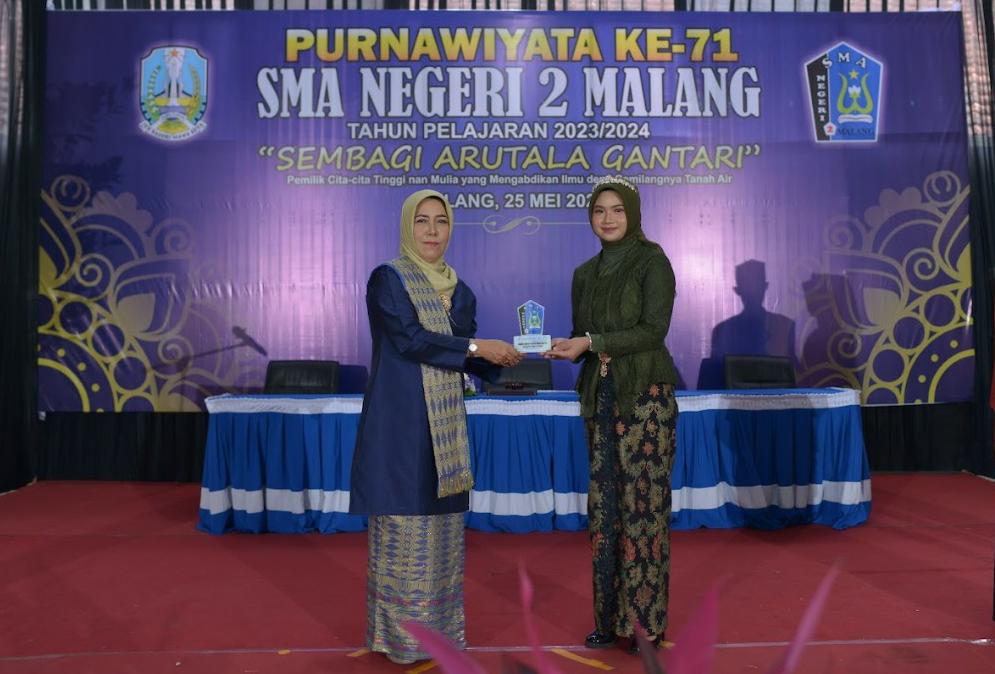 BERPRESTASI : Kepala SMAN 2 Malang Dra Fety Susilawatie MPd (kiri) memberikan cendera mata kepada perwakilan siswi Purnawiyata ke-71.