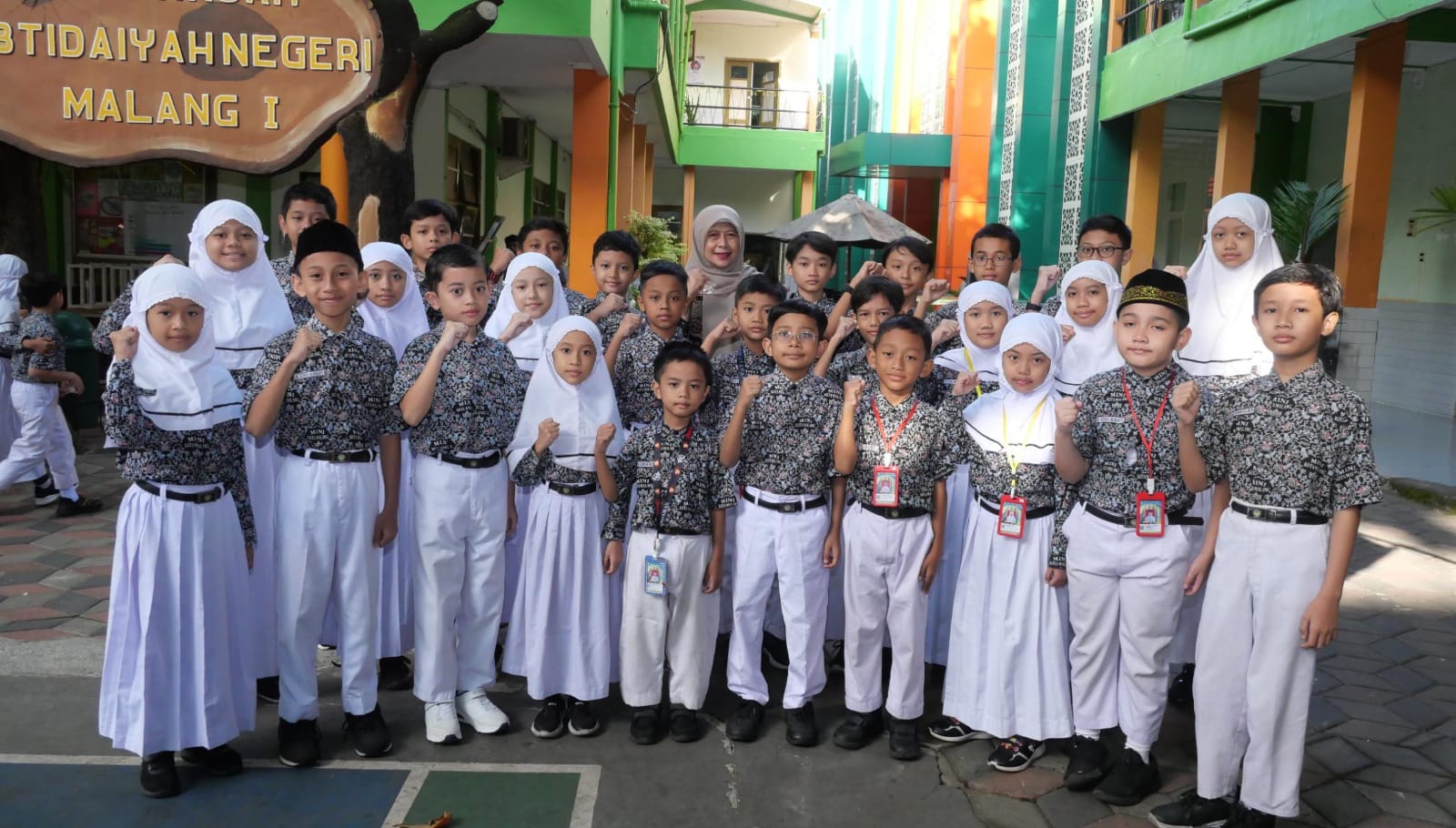 BANGGA : Kepala MIN 1 Kota Malang Hj. Siti Aisah SAg MPd (tengah) berfoto bersama 25 siswa peraih gold medal diajang IKMC.